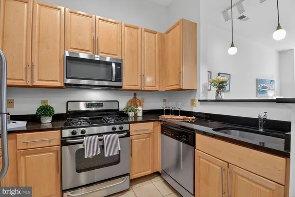 a kitchen with granite countertop a stove a sink and white cabinets