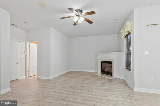 a view of an empty room with wooden floor and a fireplace