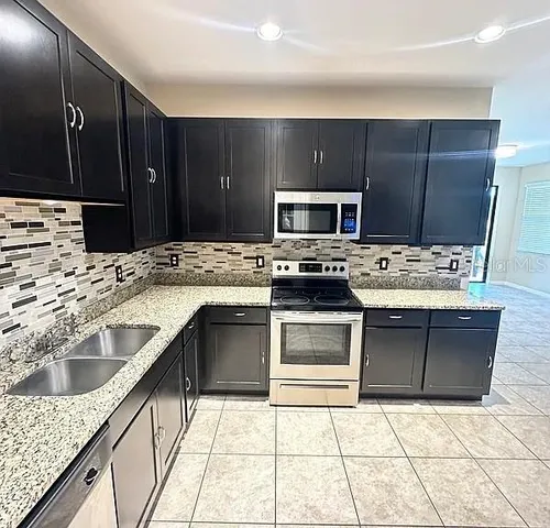 a kitchen with kitchen island granite countertop a stove a sink and a microwave