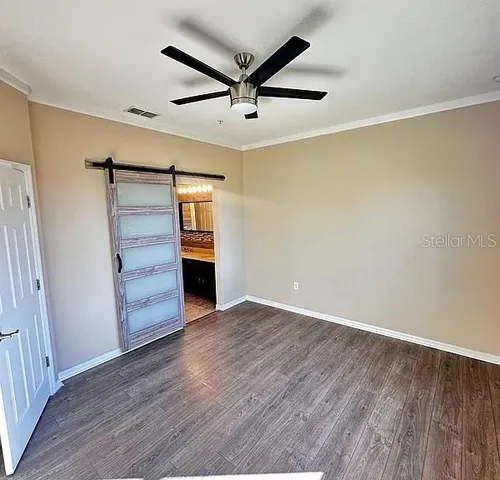 an empty room with wooden floor closet and windows