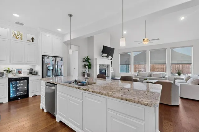 a kitchen with stainless steel appliances kitchen island a white cabinets and wooden floor