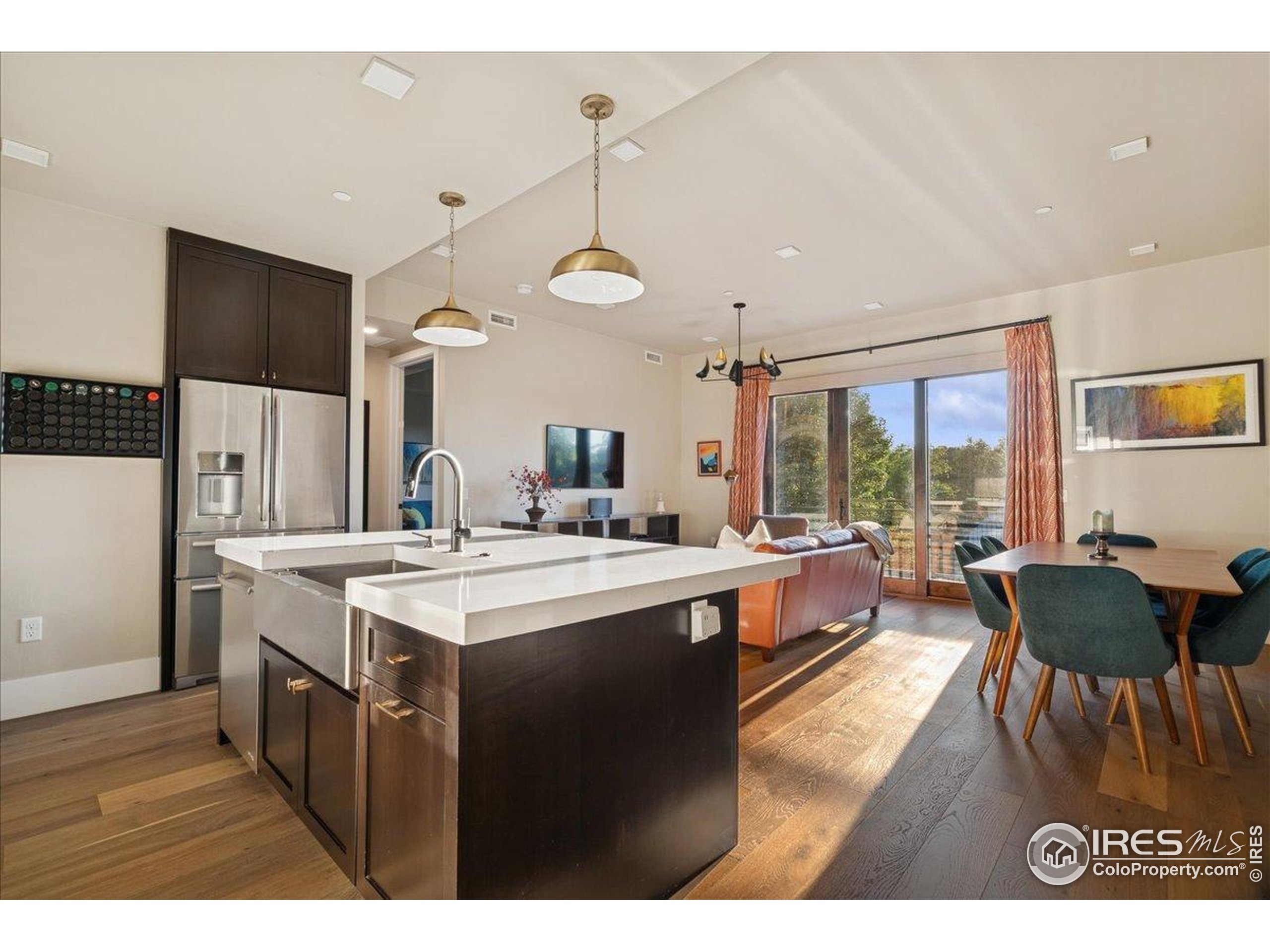 a large kitchen with kitchen island a stove a refrigerator a sink dishwasher a dining table and chairs with wooden floor