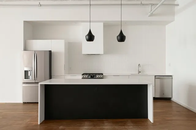 a view of an empty room with wooden floor and windows