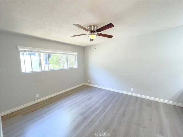an empty room with wooden floor ceiling fan and windows