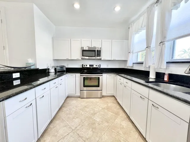 a large white kitchen with stainless steel appliances granite countertop a sink and cabinets