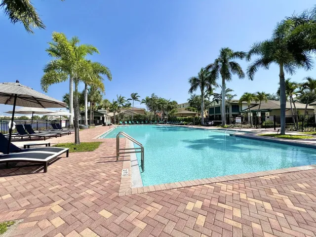 a view of a swimming pool with a garden and palm trees