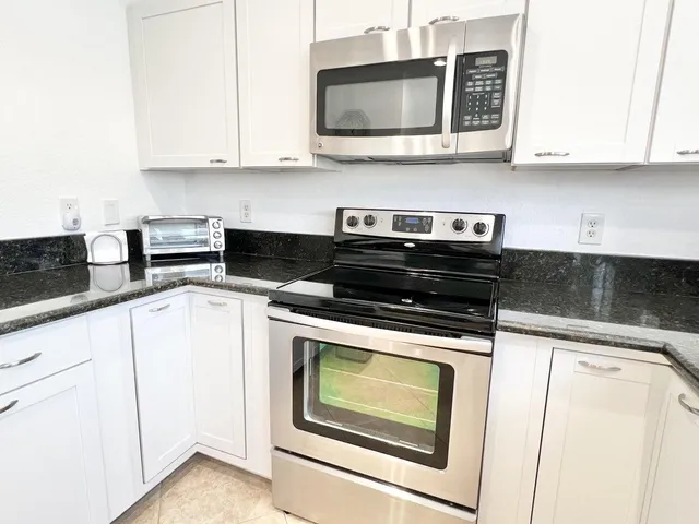 a kitchen with stainless steel appliances granite countertop white cabinets stove and microwave