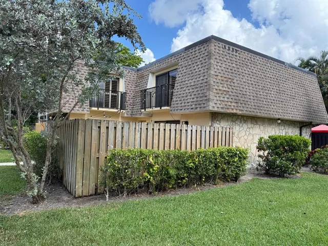a view of a backyard with plants and large trees