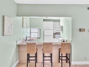 2911 Southwest 22nd Circle, Unit 37B Delray Beach, FL 33445 - Photo 50 of 51 a kitchen with kitchen island a table and chairs