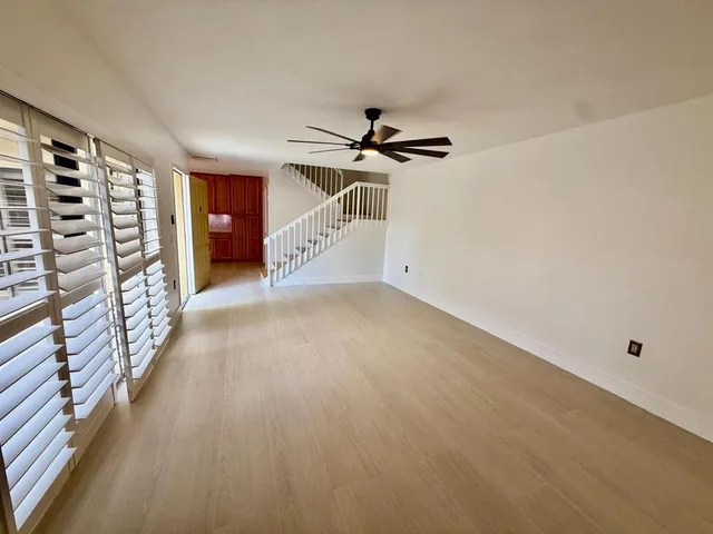 an empty room with windows and fan