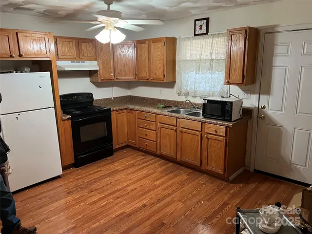 a kitchen with stainless steel appliances granite countertop a stove top oven a refrigerator a sink and dishwasher with wooden floor