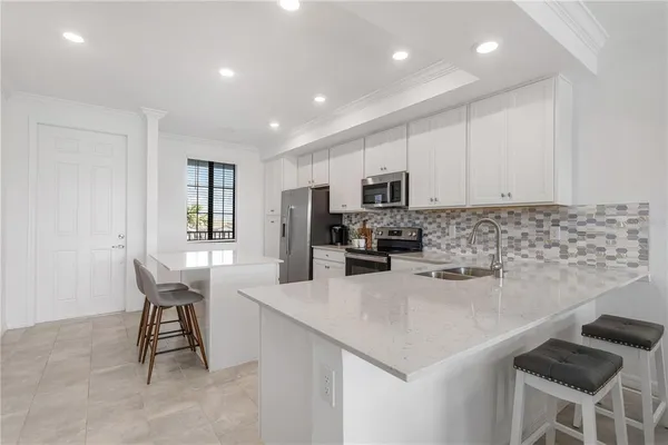 a kitchen with stainless steel appliances granite countertop a stove a sink a microwave a refrigerator white cabinets and couches