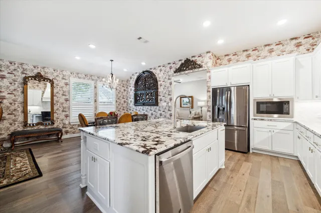 a kitchen with stainless steel appliances granite countertop a lot of counter space and wooden floors
