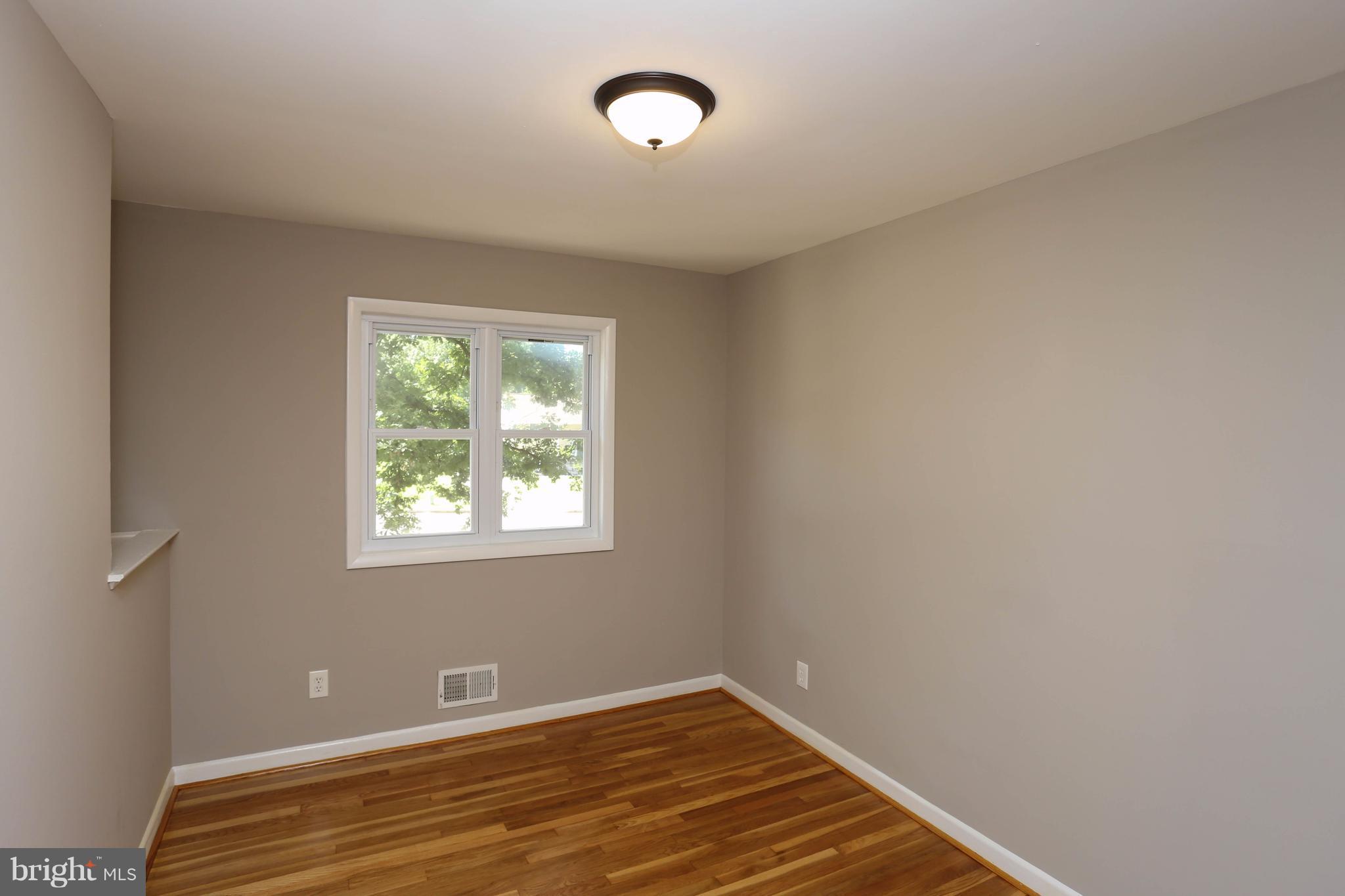 512 Crosby Road Baltimore, MD 21228 - Photo 17 of 30 a view of an empty room with wooden floor and a window