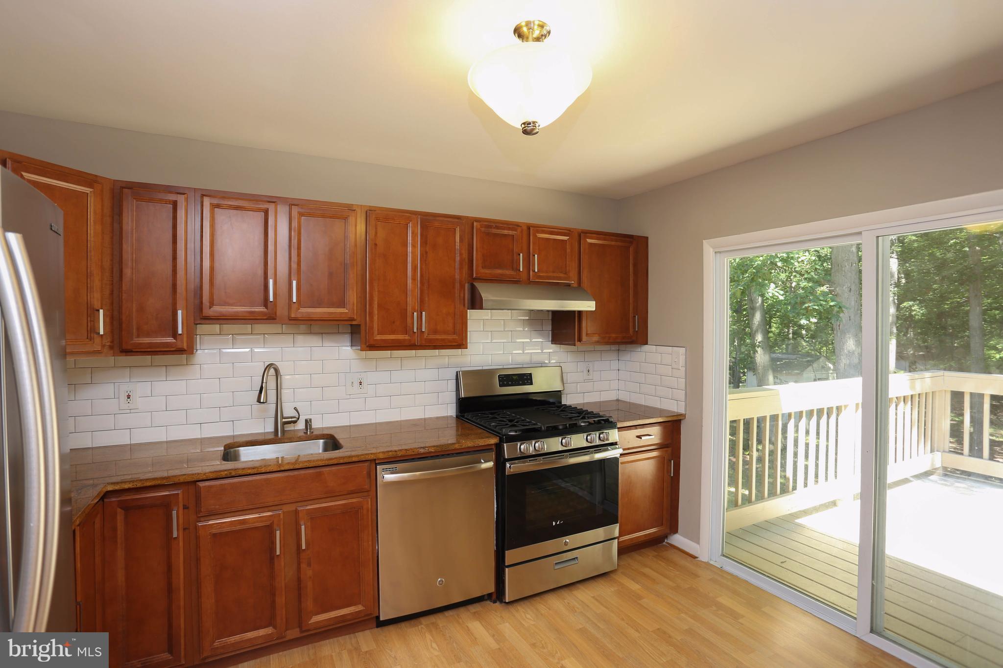512 Crosby Road Baltimore, MD 21228 - Photo 9 of 30 a kitchen with granite countertop wooden cabinets and a stove top oven