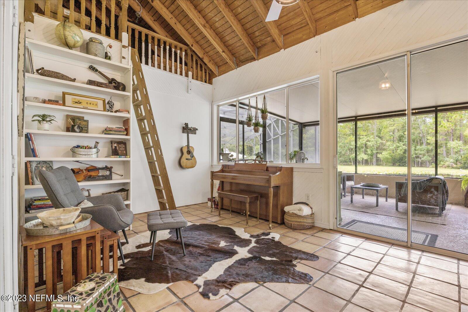 1100 Oak Ridge Road St. Augustine, FL 32086 - Photo 49 of 95 a living room with furniture a flat screen tv and floor to ceiling windows
