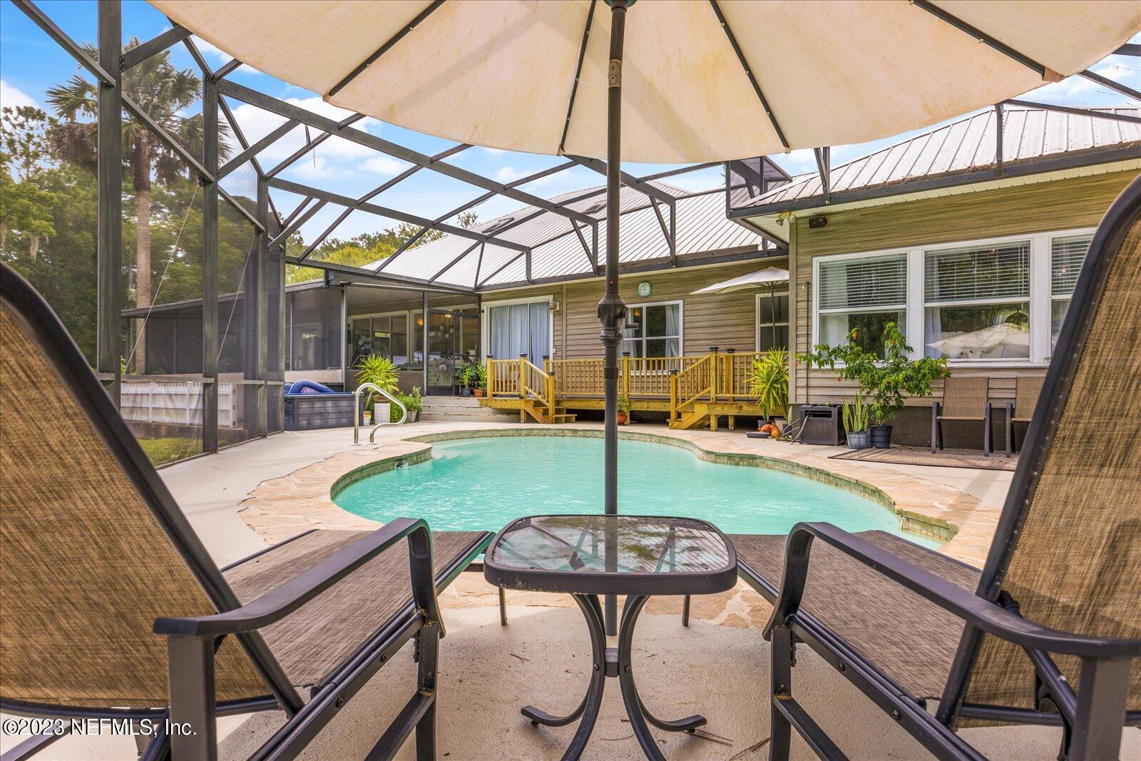 1100 Oak Ridge Road St. Augustine, FL 32086 - Photo 63 of 95 a view of a patio with table and chairs under an umbrella