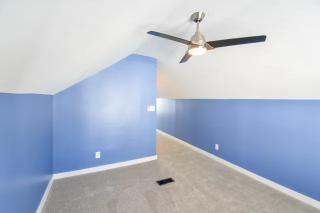 a view of a room with a ceiling fan and carpet