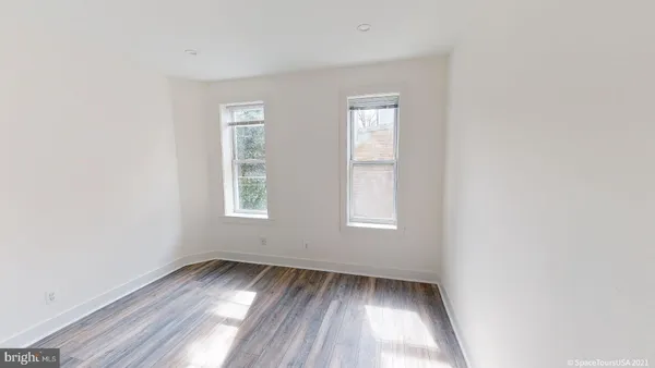 an empty room with wooden floor and windows