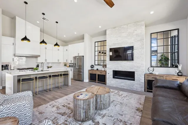 a large open kitchen with a stove a sink dishwasher and a fireplace with wooden floor