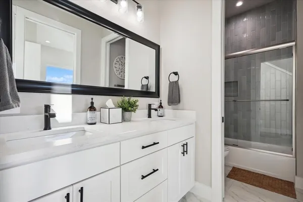 a bathroom with a double vanity sink mirror and a bathtub