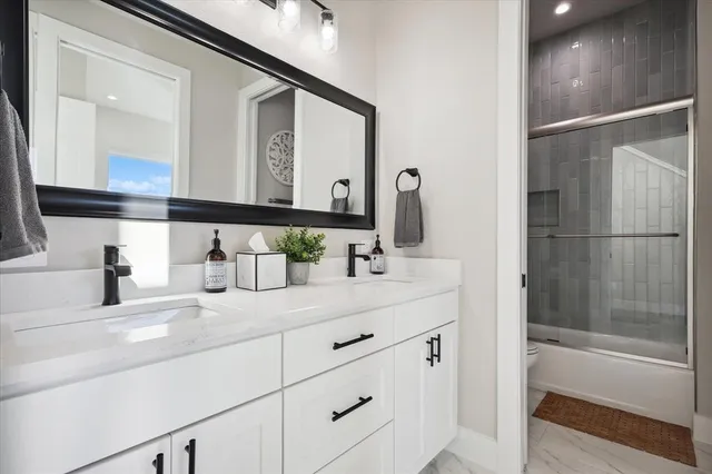 a bathroom with a double vanity sink mirror and a bathtub