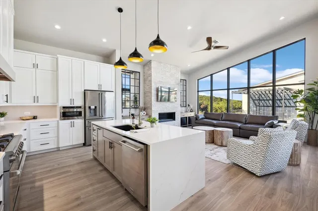 a large kitchen with kitchen island a large counter space a sink appliances and a large window