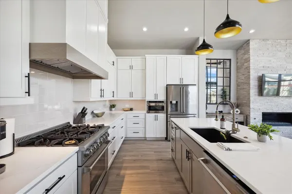 a kitchen with a stove a sink dishwasher a refrigerator and a dining table with wooden floor