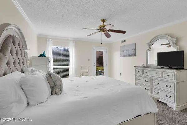 a bedroom with a large bed a flat tv screen and a dresser