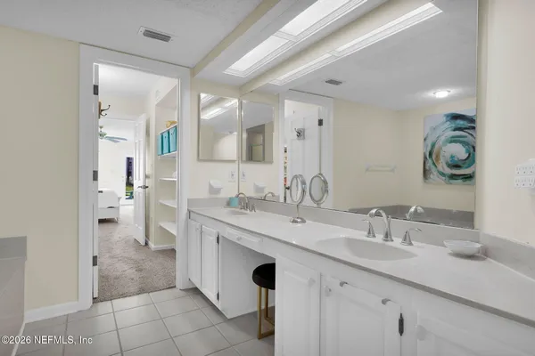 a spacious bathroom with a double vanity sink a mirror and a shower