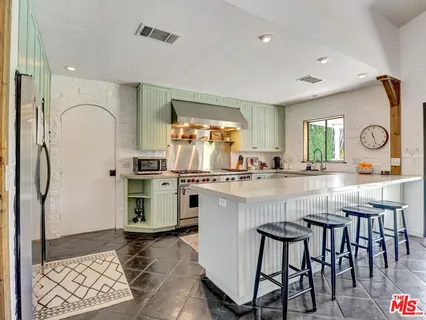 a kitchen with stainless steel appliances granite countertop a stove a sink dishwasher and a refrigerator with wooden floor