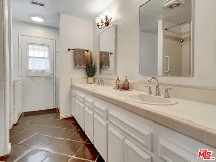 a bathroom with a double vanity sink a mirror and shower