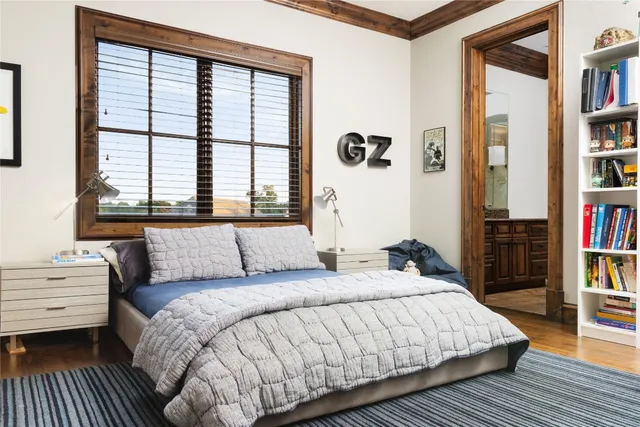 a bedroom with a bed a large window and book shelf