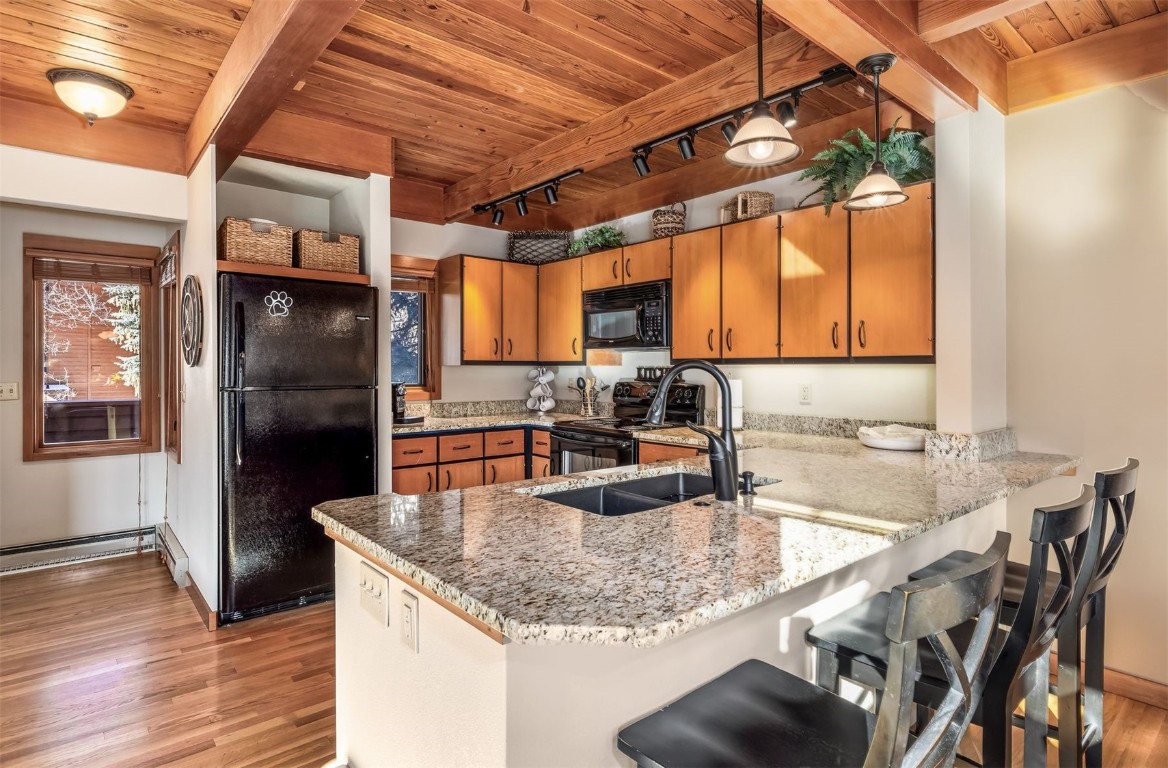 410 Tennis Club Road, Unit 1317 Keystone, CO 80435 - Photo 2 of 47 Kitchen featuring rail lighting, a breakfast bar area, black appliances, a peninsula, and light wood-type flooring
