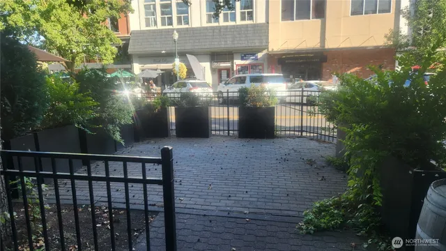 a view of a brick house with plants and large tree