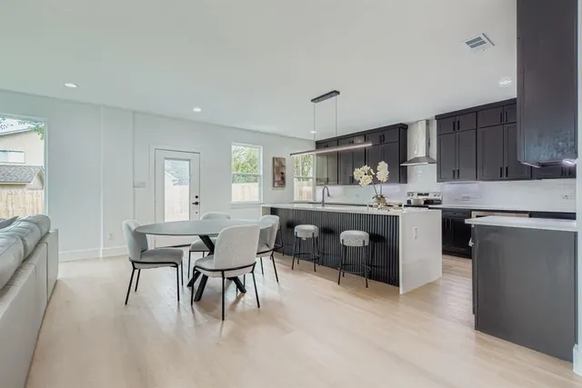a kitchen with a table chairs a sink dishwasher and cabinets