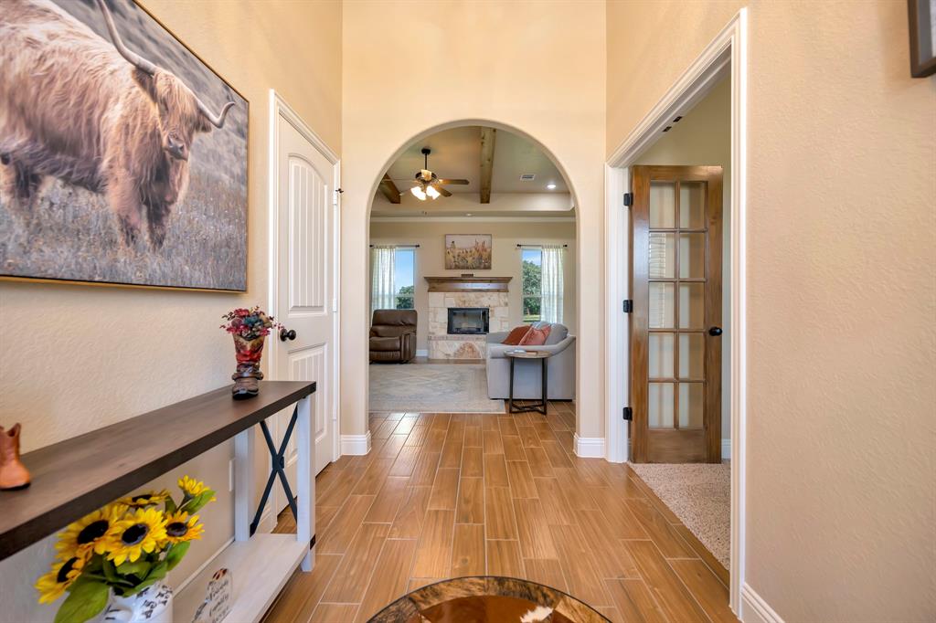 3224 North Cardinal Road Azle, TX 76020 - Photo 11 of 40 Archway entry to a living space featuring ceramic tile flooring, a wood burning fireplace with stone surround