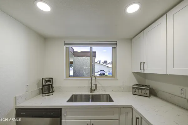 a kitchen with a refrigerator a sink dishwasher a dining table and chairs with wooden floor