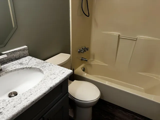 a bathroom with a granite countertop sink toilet and shower