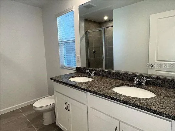 a bathroom with a granite countertop sink a toilet and a mirror