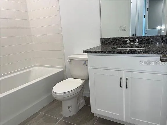 a bathroom with a granite countertop toilet and a sink