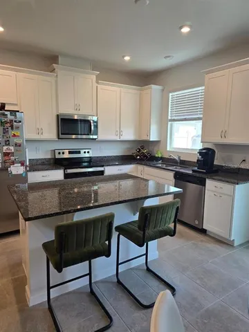 a kitchen with stainless steel appliances granite countertop a stove a sink a microwave a refrigerator and cabinets