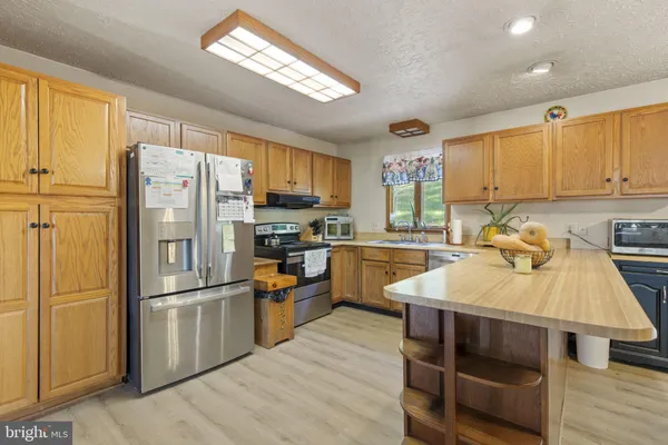 a kitchen with granite countertop a refrigerator a sink dishwasher a stove and white cabinets with wooden floor