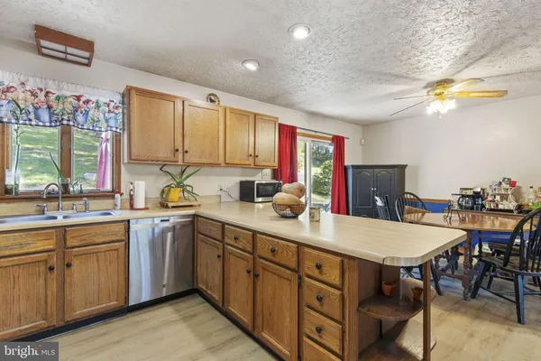 a kitchen with stainless steel appliances granite countertop a sink a stove a dining table and chairs