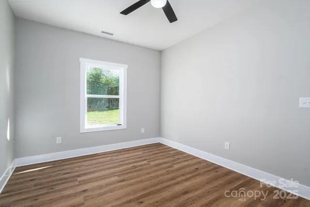 an empty room with ceiling fan and window
