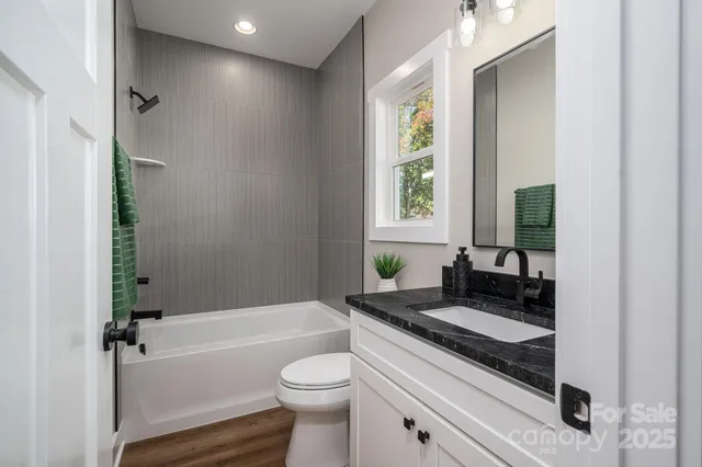 a bathroom with a granite countertop sink a toilet and bathtub