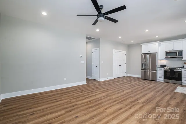 a view of kitchen with stainless steel appliances wooden floor and a window
