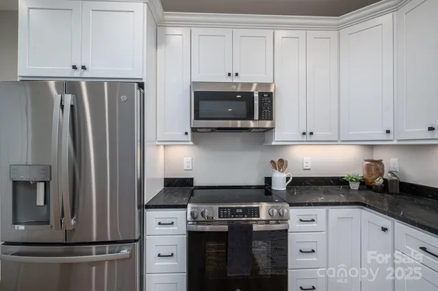 a kitchen with stainless steel appliances white cabinets and a refrigerator