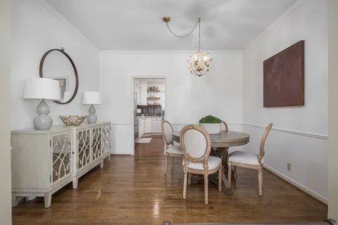 a dining room with wooden floor a chandelier a wooden table and chairs