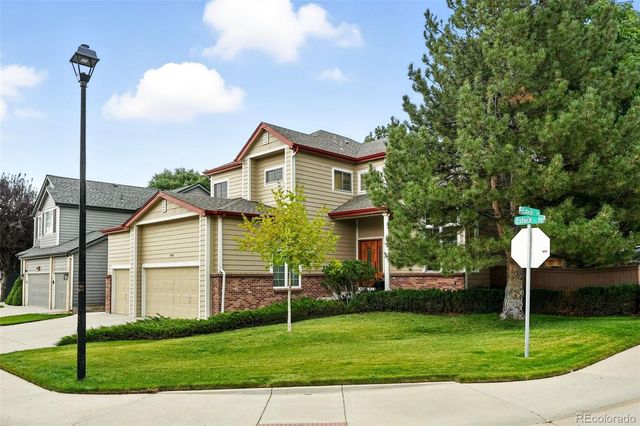 a front view of a house with a garden and trees